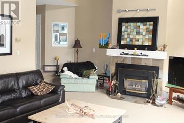 Blue Mountains townhouse for rent - A black leather couch sits in a living room with a fireplace and a painting above it.