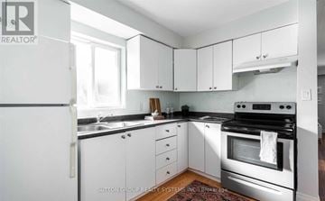 Toronto (Greenwood-Coxwell) triplex for rent - A kitchen with white cabinets and appliances.