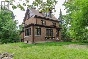 Kitchener apartment for rent - A large house with a red brick exterior and a large lawn in front.