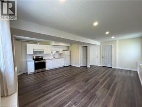 Waterloo apartment for rent - A well-lit, spacious room with wood flooring and a kitchen area in the background.