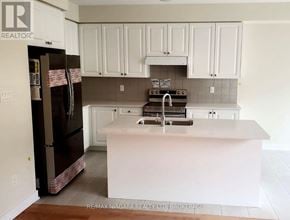 Welland (Dain City) apartment for rent - A kitchen with white cabinets and a black fridge.