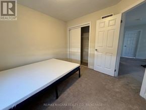 Welland (Dain City) apartment for rent - A bedroom with a bed, carpeted floor, and two doors.