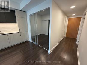 Toronto (South Riverdale) condo for rent - A spacious room with wooden floors and a glass door leading to another room.