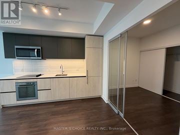 Toronto (South Riverdale) condo for rent - A kitchen with wooden cabinets and a glass door.
