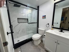 Collingwood condo for rent - A white toilet with a black handle is in a bathroom with a marble floor.