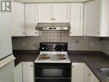 Markham (Unionville) townhouse for rent - A kitchen with white cabinets and a black stove top.