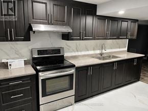 Brampton (Sandringham-Wellington) townhouse for rent - A kitchen with black cabinets and a stove top oven.