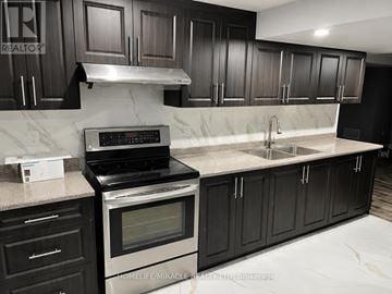 Brampton (Sandringham-Wellington) townhouse for rent - A kitchen with black cabinets and a stove top oven.
