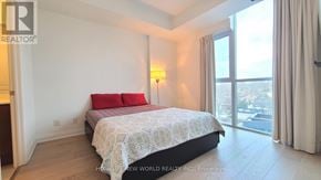 Mississauga (Port Credit) condo for rent - A bedroom with a large bed and a view of the city.
