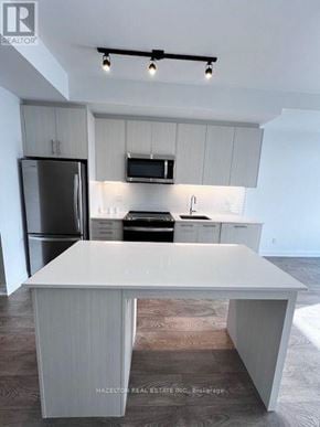Toronto (East End-Danforth) condo for rent - A modern kitchen with a white island and stainless steel appliances.