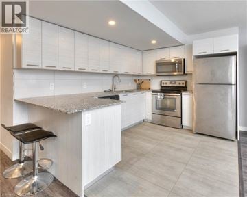Waterloo townhouse for rent - A modern kitchen with white cabinets and stainless steel appliances.