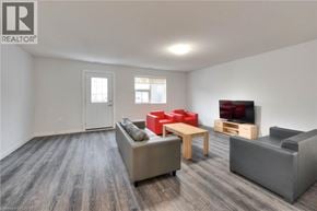 Waterloo townhouse for rent - A living room with a grey couch, red chairs, and a wooden table.