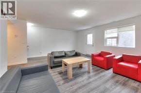 Waterloo townhouse for rent - A living room with a grey couch, a wooden table, and red chairs.