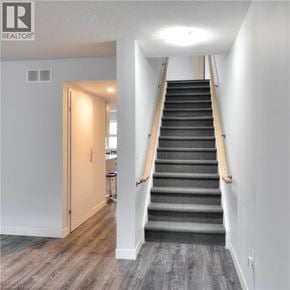 Waterloo townhouse for rent - A staircase with a wooden handrail and a carpeted runner.
