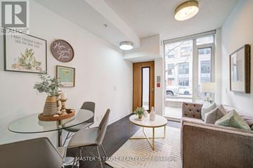 Toronto (Waterfront Communities) townhouse for rent - A living room with a glass table and chairs, a sofa, and a framed picture on the wall.