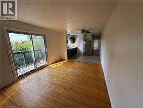Kitchener apartment for rent - A room with wooden flooring and a sliding glass door leading to a balcony.
