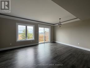 Petawawa townhouse for rent - A spacious room with wooden floors and a large window overlooking a fence.