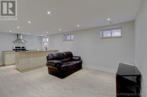 Barrie (Codrington) apartment for rent - A brown leather couch sits in a white room with a wooden floor.