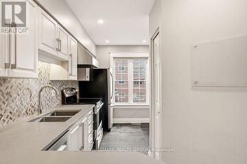 Ottawa townhouse for rent - A kitchen with a black refrigerator and white cabinets.
