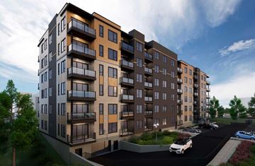 Moncton apartment for rent - A modern apartment building with a parking lot in front.