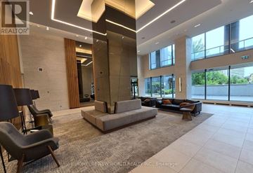 Toronto (Flemingdon Park) condo for rent - A spacious living room with a large grey sofa and a wooden accent wall.