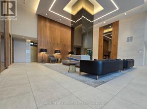 Toronto (Flemingdon Park) condo for rent - A spacious lobby with a black sofa and wooden accents.