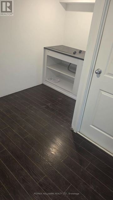 Pickering (Bay Ridges) apartment for rent - A white door is open to a room with a black floor and a white cabinet with a microwave on top.