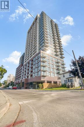 Mississauga (Port Credit) condo for rent - A tall building with many windows is situated on a street corner.