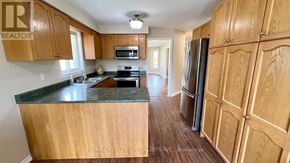 Barrie (Painswick South) apartment for rent - A kitchen with wooden cabinets and a black countertop.