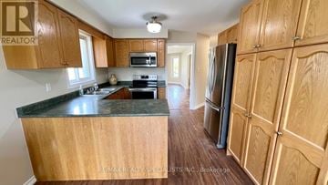 Barrie (Painswick South) apartment for rent - A kitchen with wooden cabinets and a black countertop.