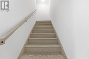 Niagara Falls (Clifton Hill) townhouse for rent - A staircase with a wooden handrail and steps leading upwards.
