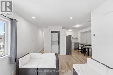 Niagara Falls (Clifton Hill) townhouse for rent - A white couch sits in a living room with a kitchen in the background.
