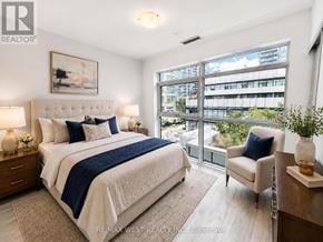Toronto (Mimico) condo for rent - A bedroom with a large bed and a view of a cityscape through the window.
