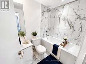 Toronto (Mimico) condo for rent - A white bathroom with a marble wall and a toilet.