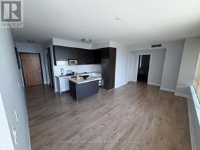 Toronto (Mimico) condo for rent - A spacious room with wooden flooring and a kitchen area with a counter and cabinets.