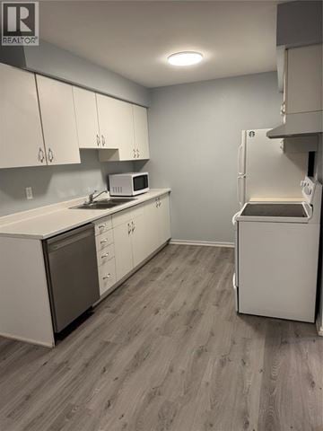 Sarnia townhouse for rent - A kitchen with white cabinets and a microwave.