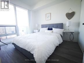 Toronto (Waterfront Communities) condo for rent - A bedroom with a large bed and a heart-shaped decoration on the wall.