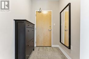 Ottawa condo for rent - A room with a wooden door, a black cabinet, and a mirror on the wall.