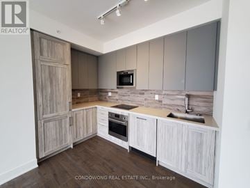 Vaughan (Concord) condo for rent - A kitchen with wooden cabinets and a stone backsplash.