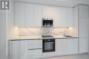 Toronto (Waterfront Communities) condo for rent - A modern kitchen with white cabinets and a black oven.