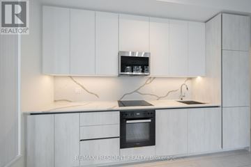 Toronto (Waterfront Communities) condo for rent - A modern kitchen with white cabinets and a black oven.