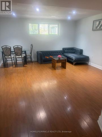 Toronto (Morningside) apartment for rent - A living room with a black couch and wooden floors.