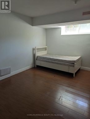 Toronto (Morningside) apartment for rent - A white bed sits in a room with wooden floors and white walls.