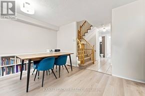 Newmarket (Woodland Hill) townhouse for rent - A room with a wooden table and blue chairs with a staircase in the background.