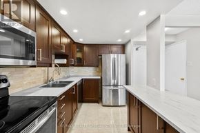 Mississauga (Fairview) condo for rent - A modern kitchen with dark wood cabinets and stainless steel appliances.