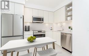 Mississauga (Central Erin Mills) house for rent - A modern kitchen with a white table and chairs, a refrigerator, a microwave, and a stove.