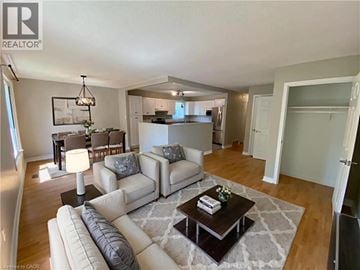 Welland apartment for rent - A well-lit living room with a white sofa set and a coffee table.