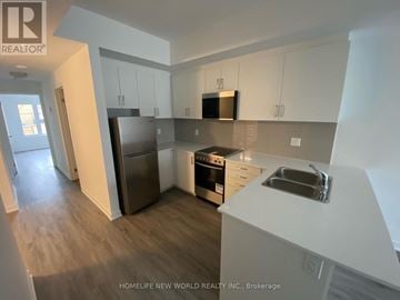 Toronto (Englemount-Lawrence) townhouse for rent - A kitchen with white cabinets and a stainless steel refrigerator.