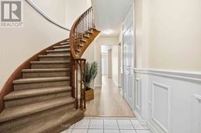 Clarington (Courtice) townhouse for rent - A staircase with a wooden handrail and beige carpeted steps leads to a bright hallway.
