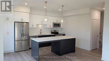Guelph (Riverside Park) townhouse for rent - A modern kitchen with a refrigerator, microwave, and oven.
